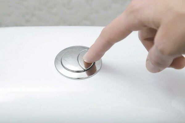 Mains actionnant les deux boutons d'une chasse d'eau