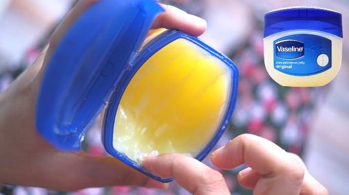 Pot de vaseline entouré d'ingrédients naturels comme des pétales de rose et du citron