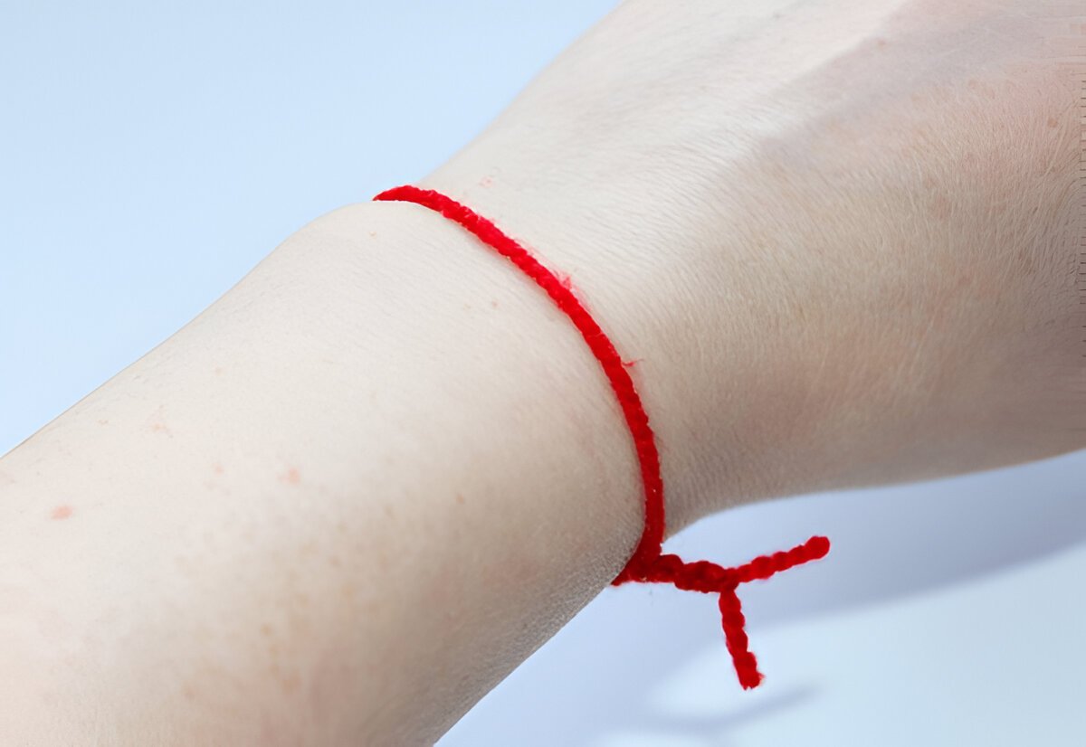 Personne attachant un fil rouge à un poignet