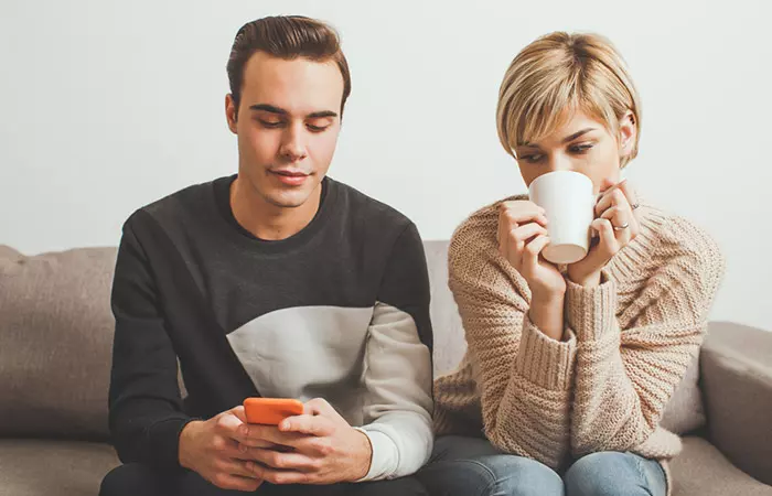 Homme distant avec sa compagne, absorbé par son téléphone