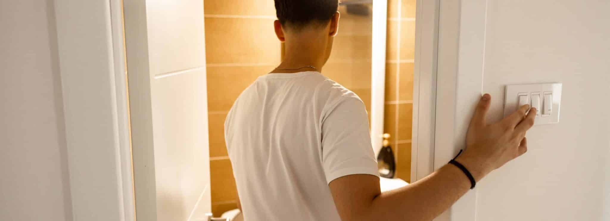 Homme éteignant la lumière dans une pièce carrelée