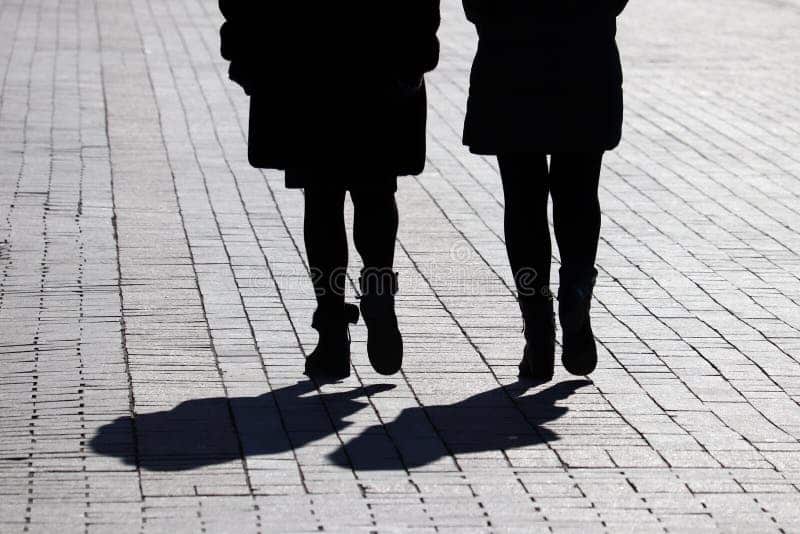 Deux femmes marchant côte à côte dans une rue en pente, symbolisant une relation naissante