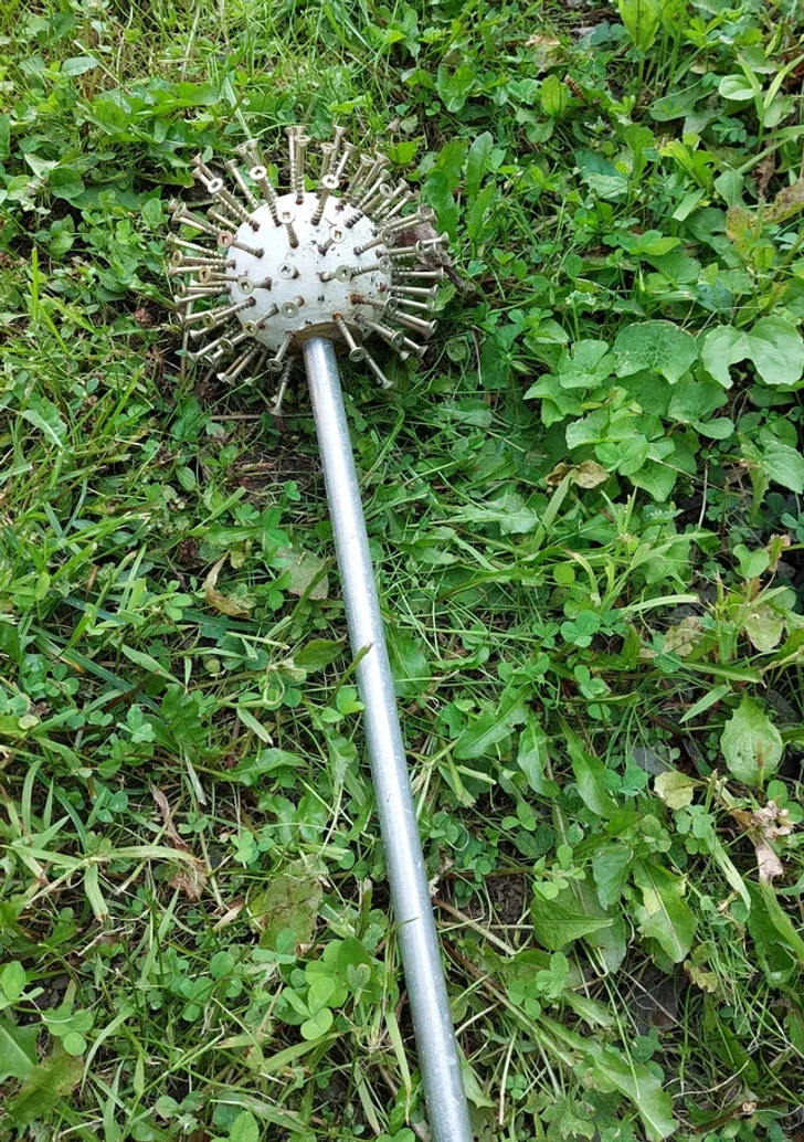 Boule en bois hérissée de vis, posée sur un lit de gravier