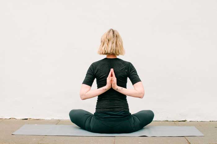 Femme souriante pratiquant le Gyan Mudra dans un cadre naturel et serein