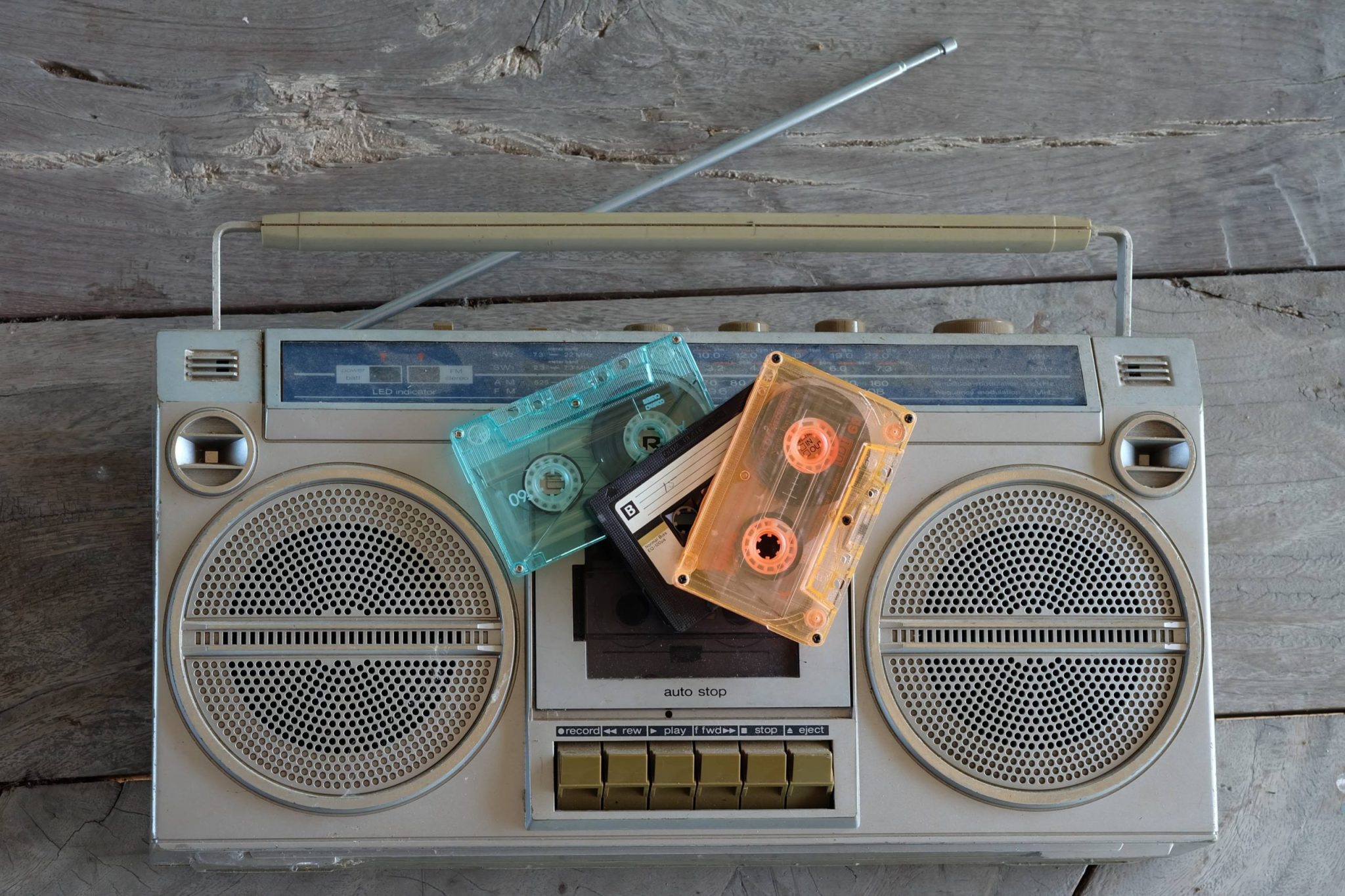Une main tenant une cassette audio et un stylo, prête à noter le nom d'un morceau.