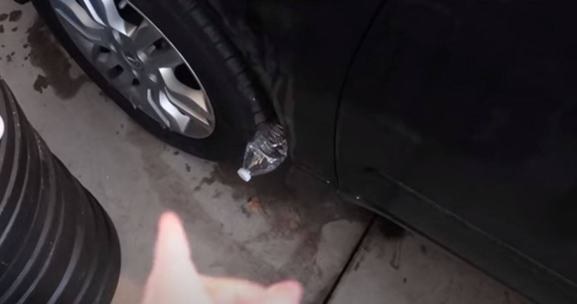 Détail d'un pneu de voiture avec une bouteille en plastique