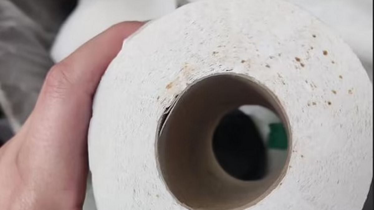 Femme réfléchissant devant un distributeur de papier toilette