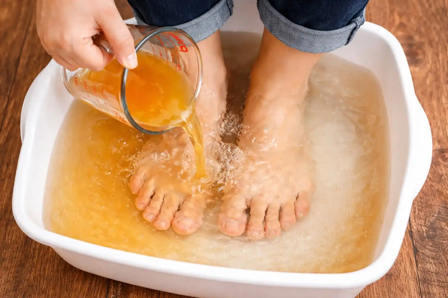 Femme relaxée les pieds dans une bassine, illustrant un moment de détente