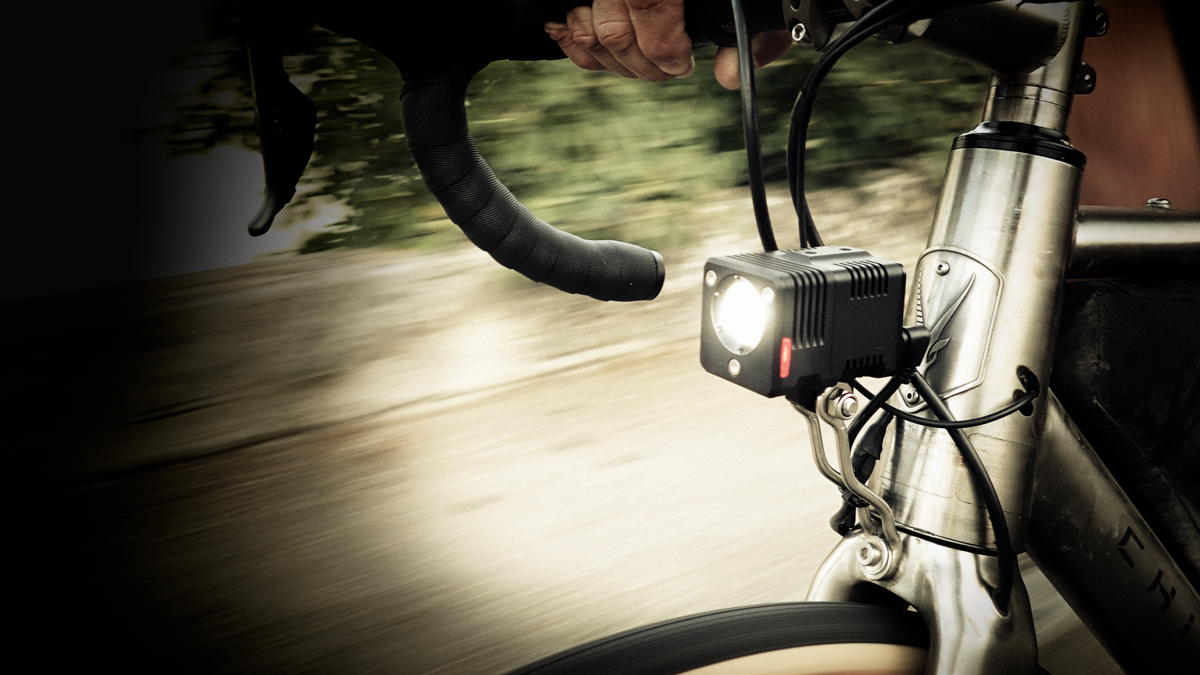 Bannière montrant un vélo ancien avec une dynamo sur la roue avant, éclairant un chemin de campagne la nuit.