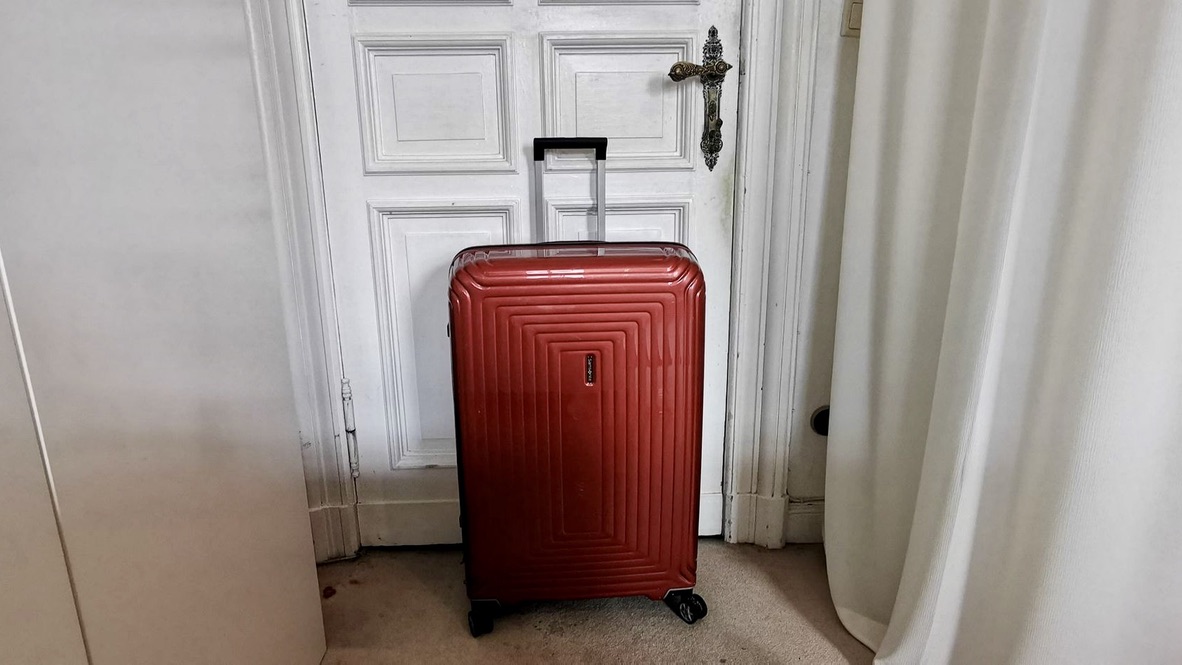 Un homme avec des valises devant une porte, évoquant un retour inattendu et mal préparé.