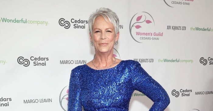 Jamie Lee Curtis pose souriante dans une limousine, vêtue d'un haut noir et de dentelle