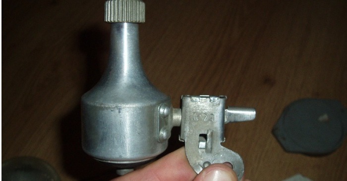 Photo en gros plan d'un objet métallique cylindrique rouillé, partiellement couvert de terre, tenu dans une main.