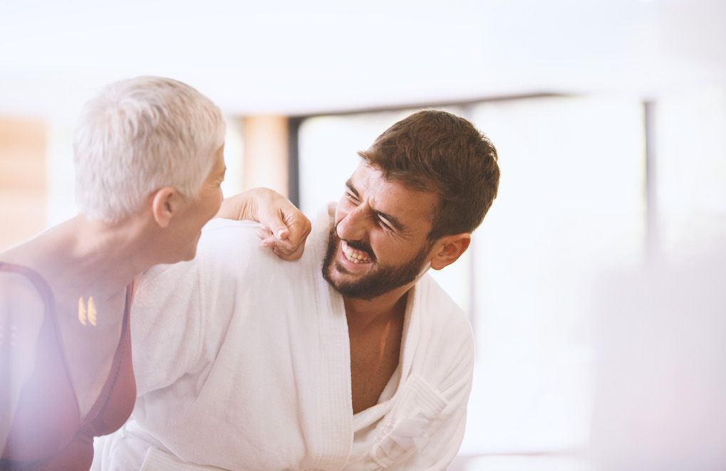 Couple souriant, une femme plus âgée et un homme plus jeune discutant complice dans un café