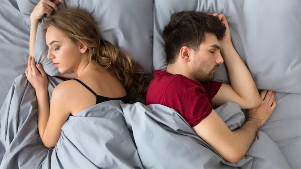 Couple dormant dos à dos dans un lit, illustrant la position de sommeil