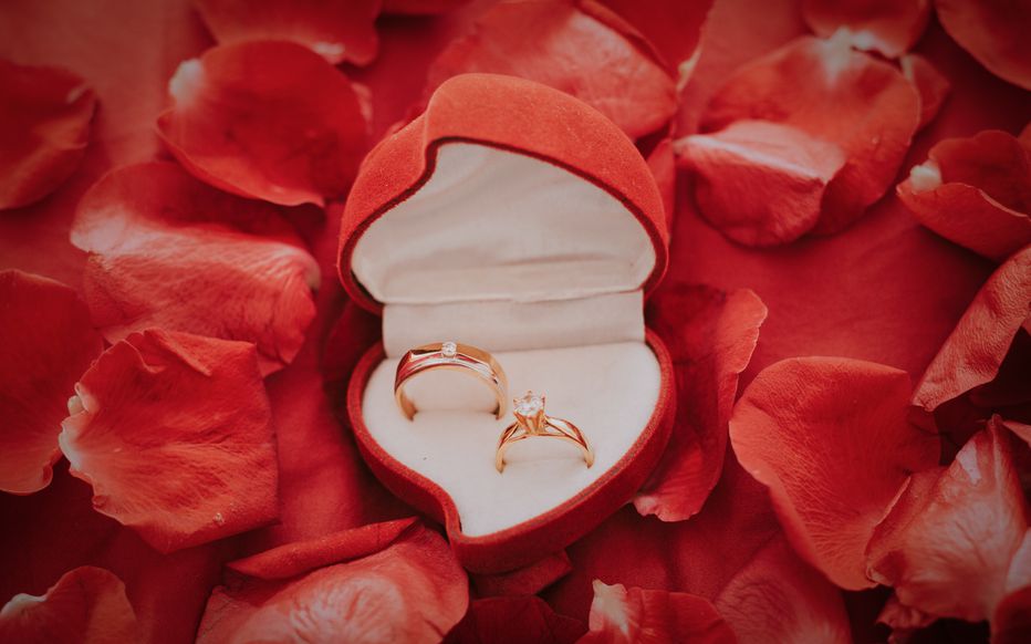 L'homme, désormais bien habillé, s'agenouille et tend un écrin à la jeune femme émerveillée