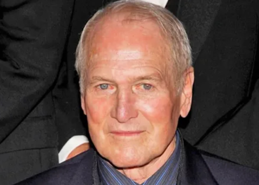 Paul Newman assis, regardant au loin, barbe fournie