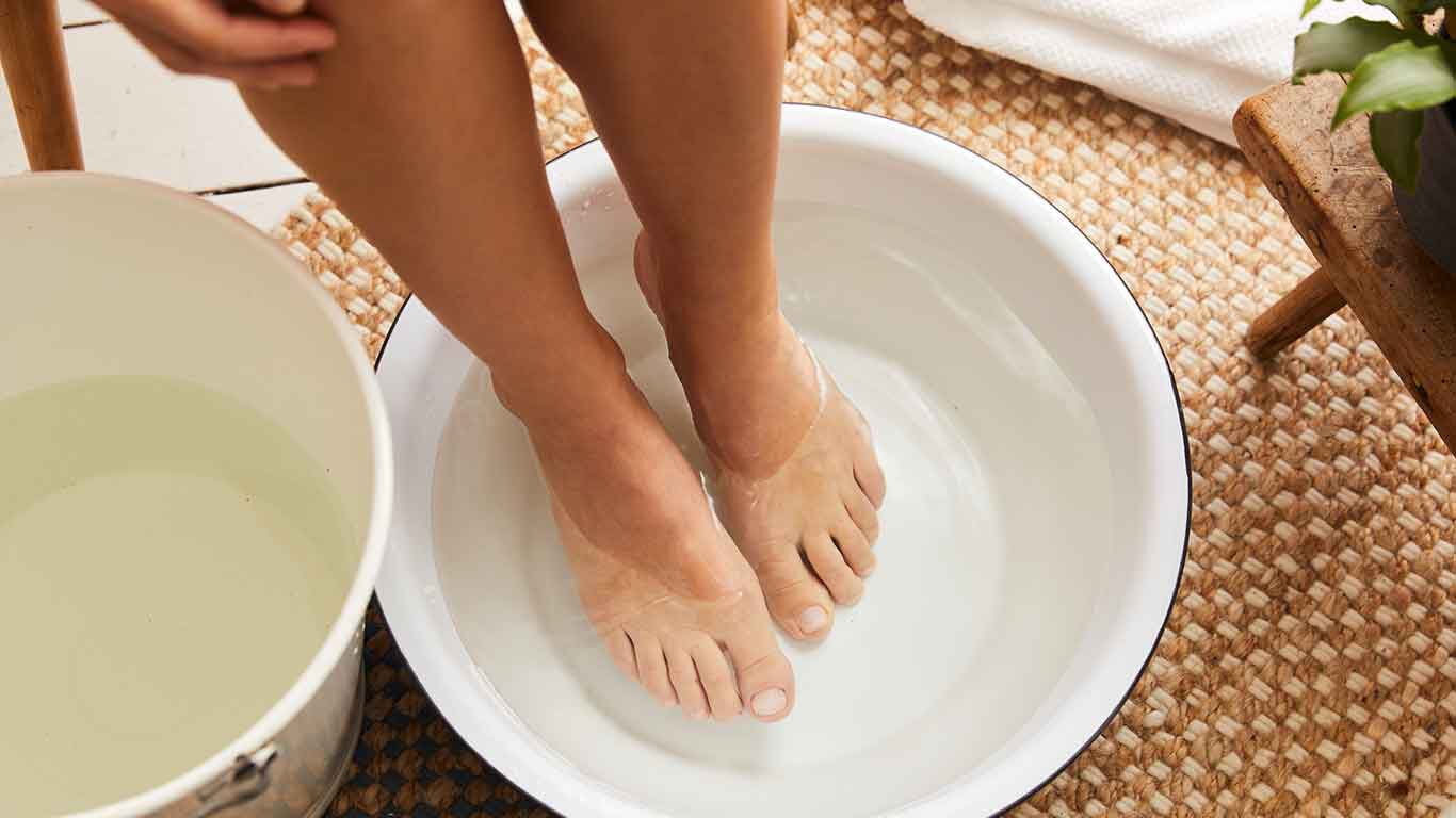 Personne préparant un bain de pieds relaxant dans une bassine