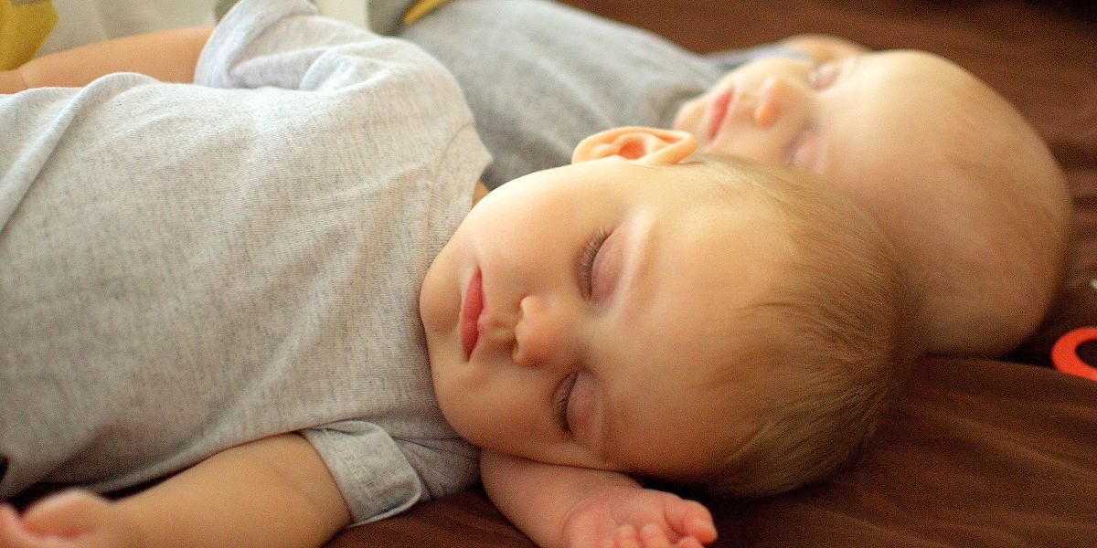 Une mère et son fils adolescent regardant deux bébés endormis