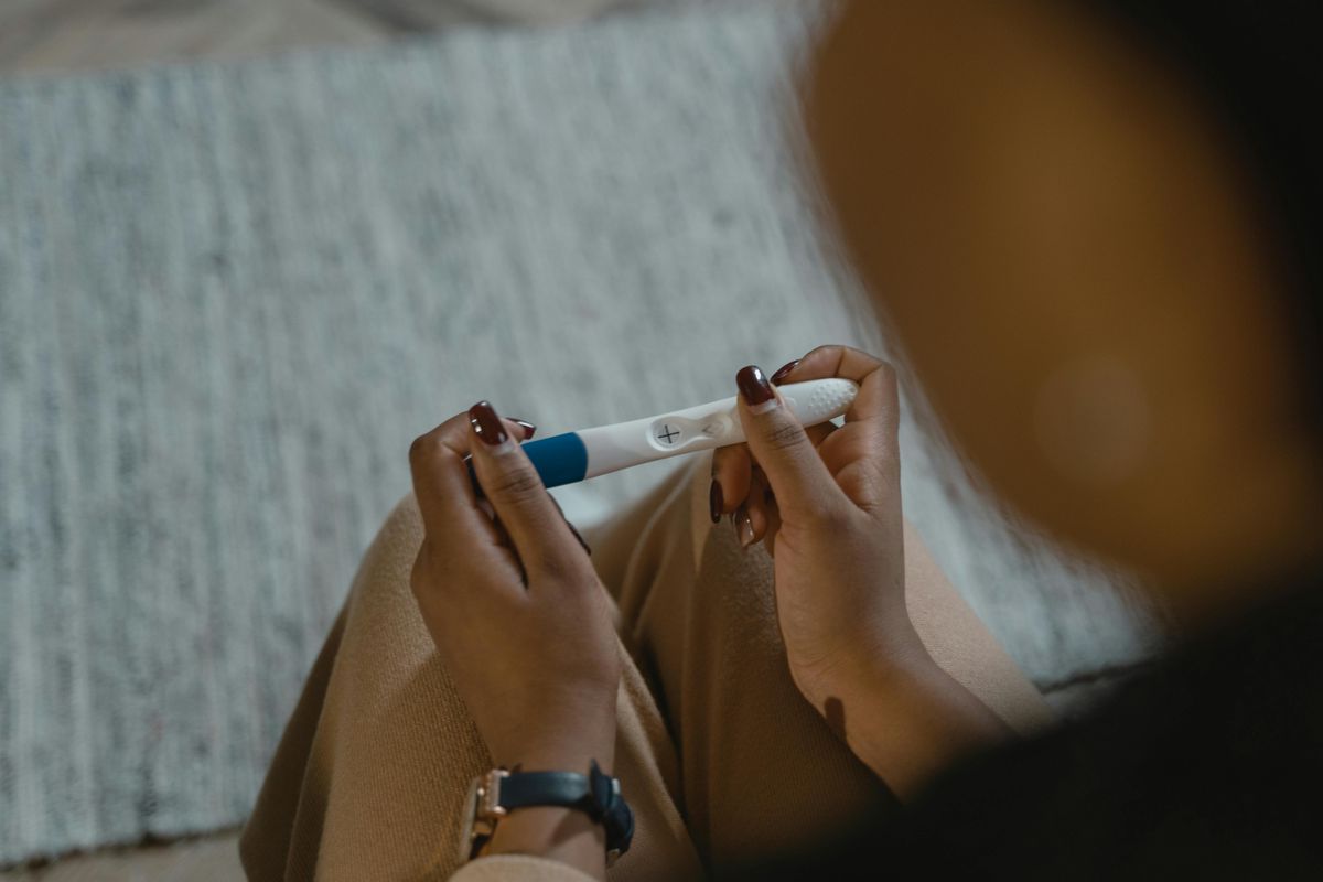 Une jeune femme assise, le regard pensif, dans un intérieur simple.