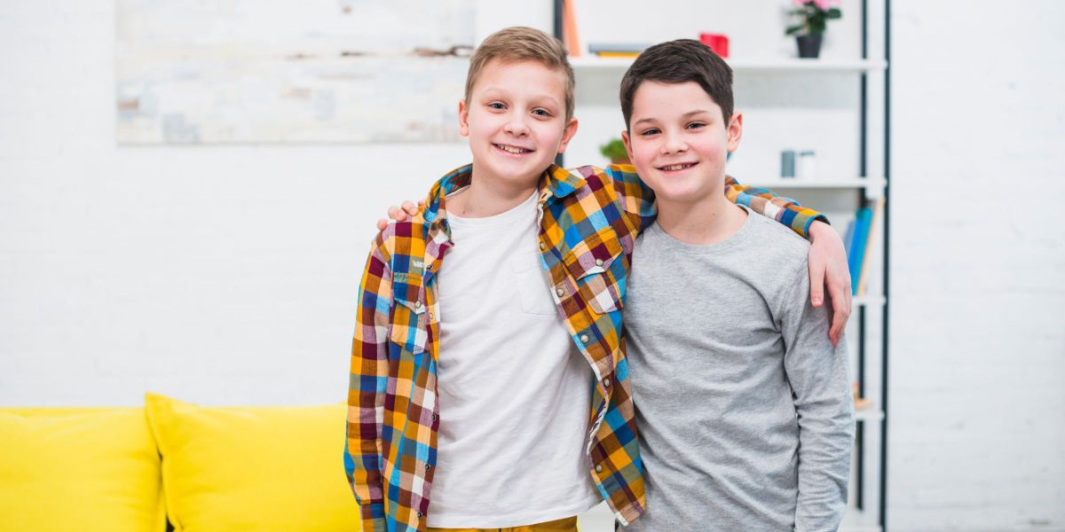 Deux petits garçons se regardant, l'air intrigué, sur une aire de jeux ensoleillée