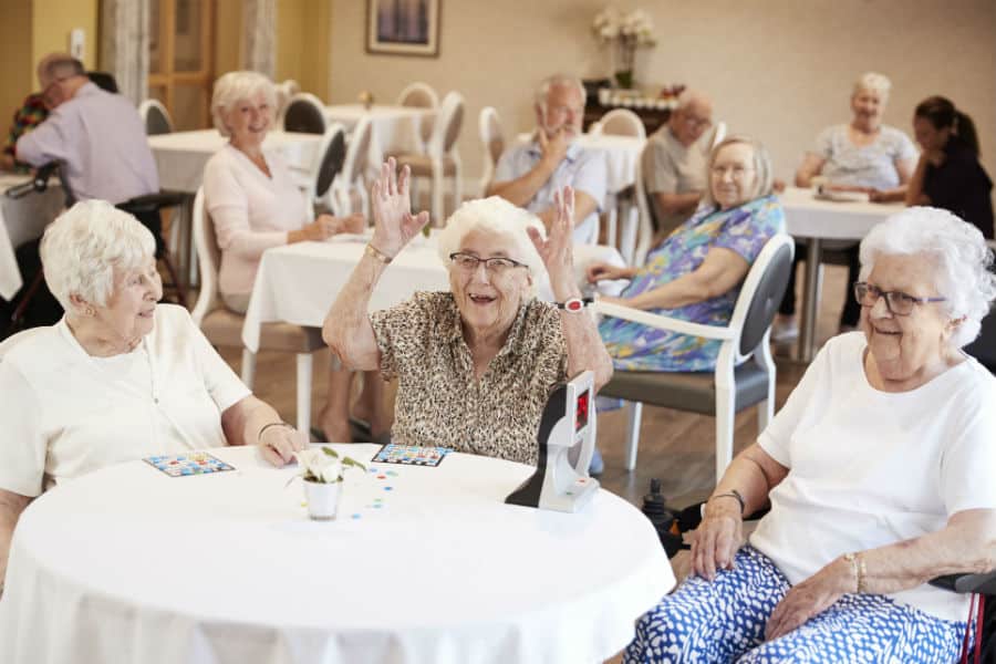 Un animateur sourit et encourage un petit groupe de résidents lors d'une activité de gymnastique douce.