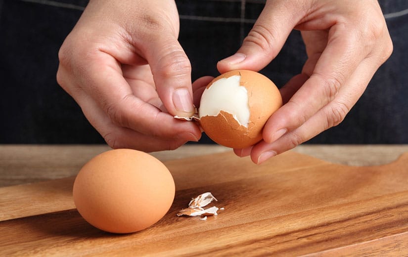 Œuf dur parfaitement écalé sur une planche en bois