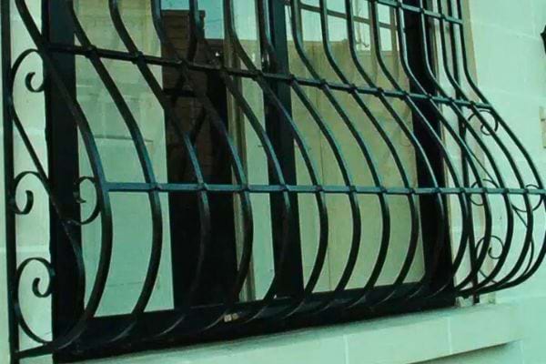 Fenêtre avec grille bombée blanche sur une façade de maison