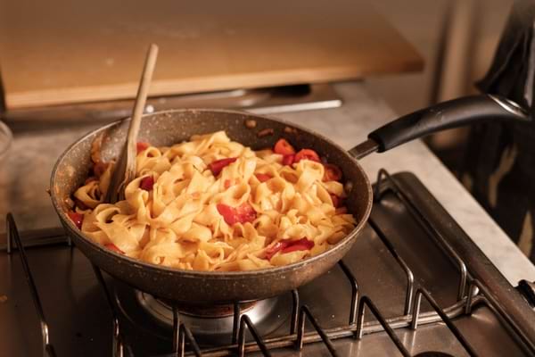 Pâtes aux tomates cuites directement dans une poêle sur une gazinière.