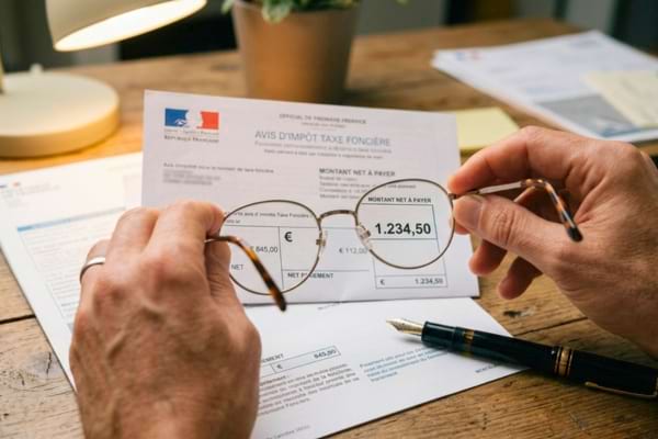 mains tenant des lunettes de lecture posées sur un avis d