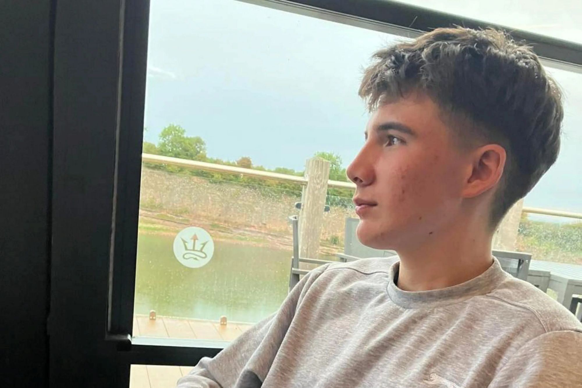 An image collage containing 1 images, Image 1 shows Sam Coutts sitting indoors in a grey sweatshirt and looking out of a window