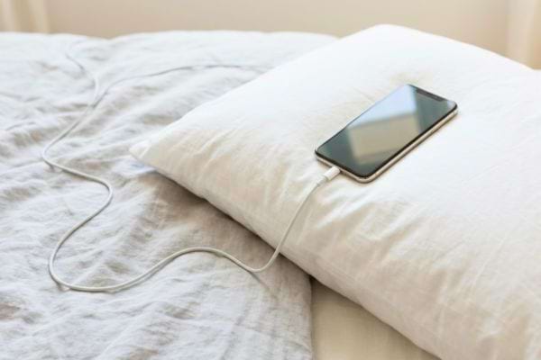 Smartphone en charge posé sur un oreiller sur un lit