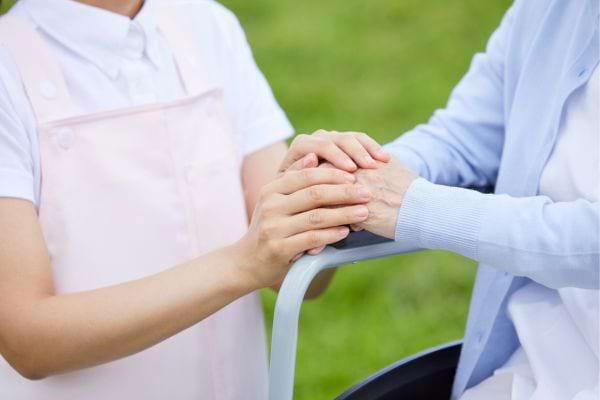Une infirmière tient tendrement les mains d'une patiente