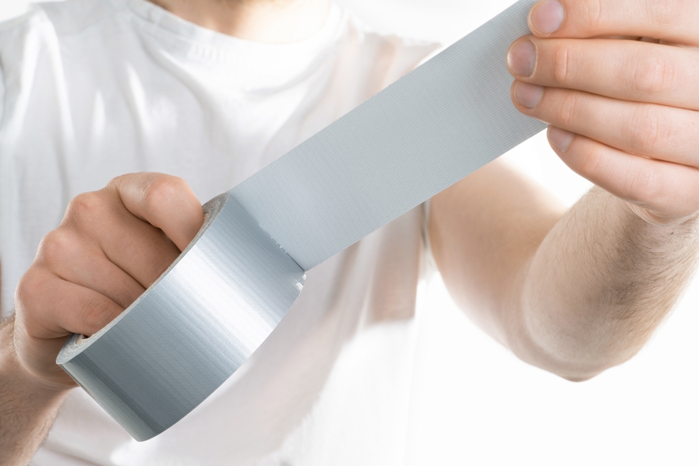 Close up image of man holding adhesive duct tape white background.