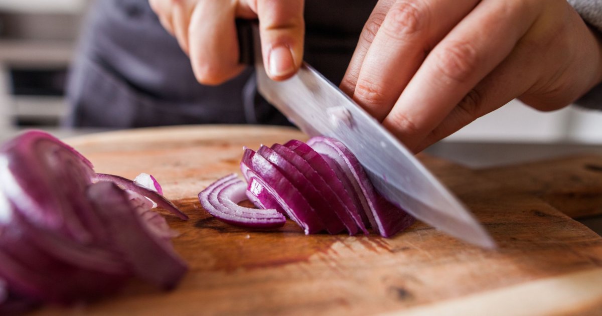 Personne coupant un oignon avec un couteau, astuces pour éviter de pleurer