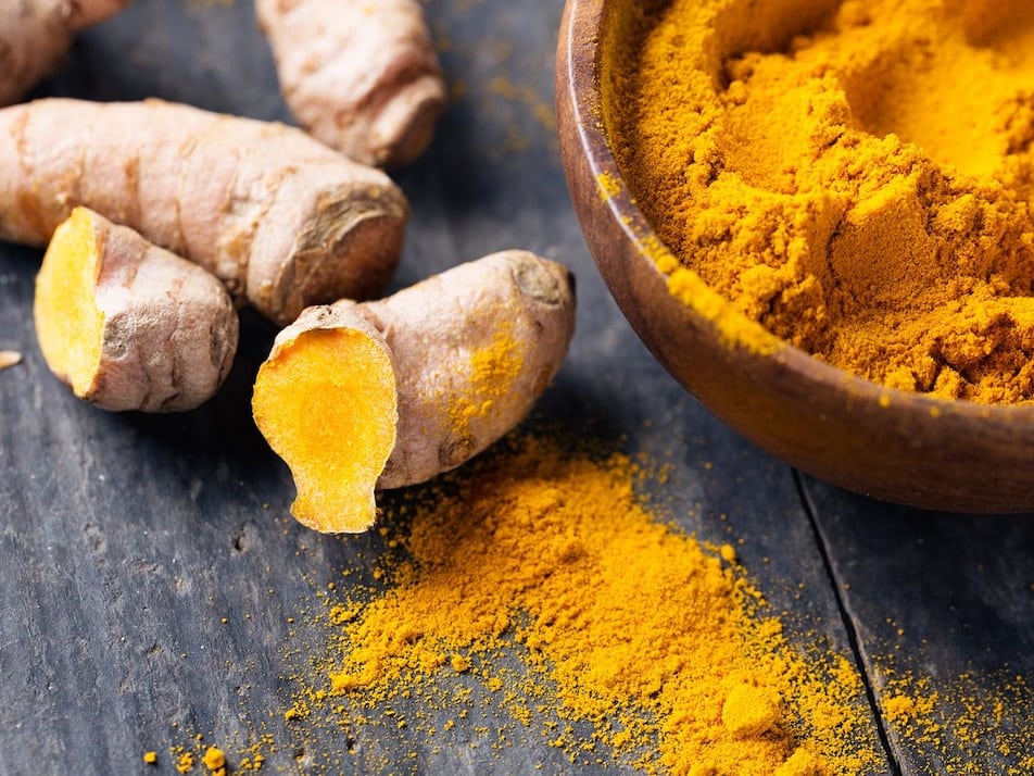 Cuillère et pot de curcuma en poudre, ingrédients naturels pour les plantes