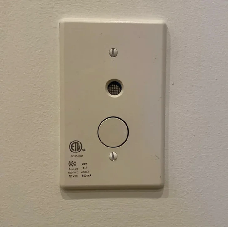 Boîtier blanc avec écran et trou rond fixé sur un mur près d'une piscine