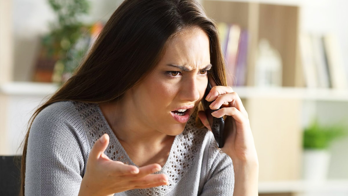 Une femme souriante et sereine tient un téléphone à l'oreille