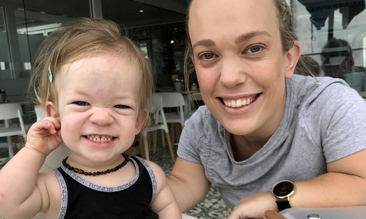 Charli, souriante, tenant l'un de ses enfants dans ses bras, un regard plein de tendresse.