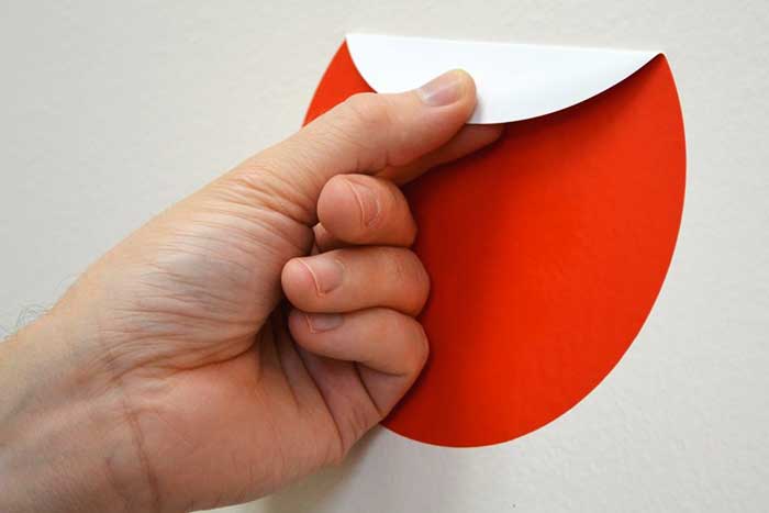 Personne utilisant un sèche-cheveux pour décoller un autocollant sur une vitre de voiture