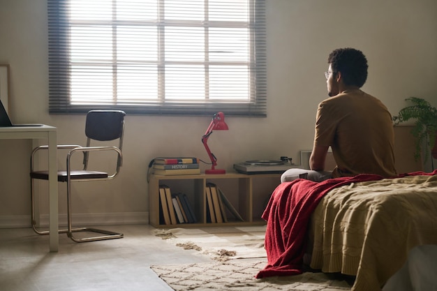 Homme assis seul dans une chambre sombre