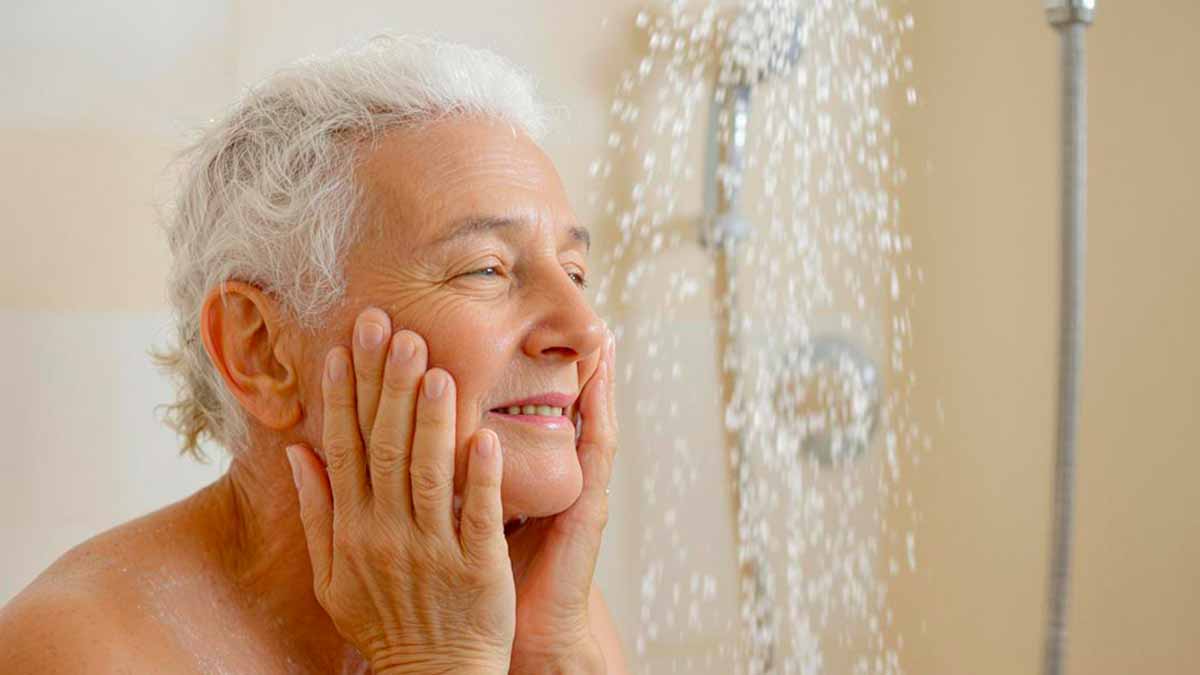Une personne âgée réfléchissant à sa routine de douche, l'air sereine