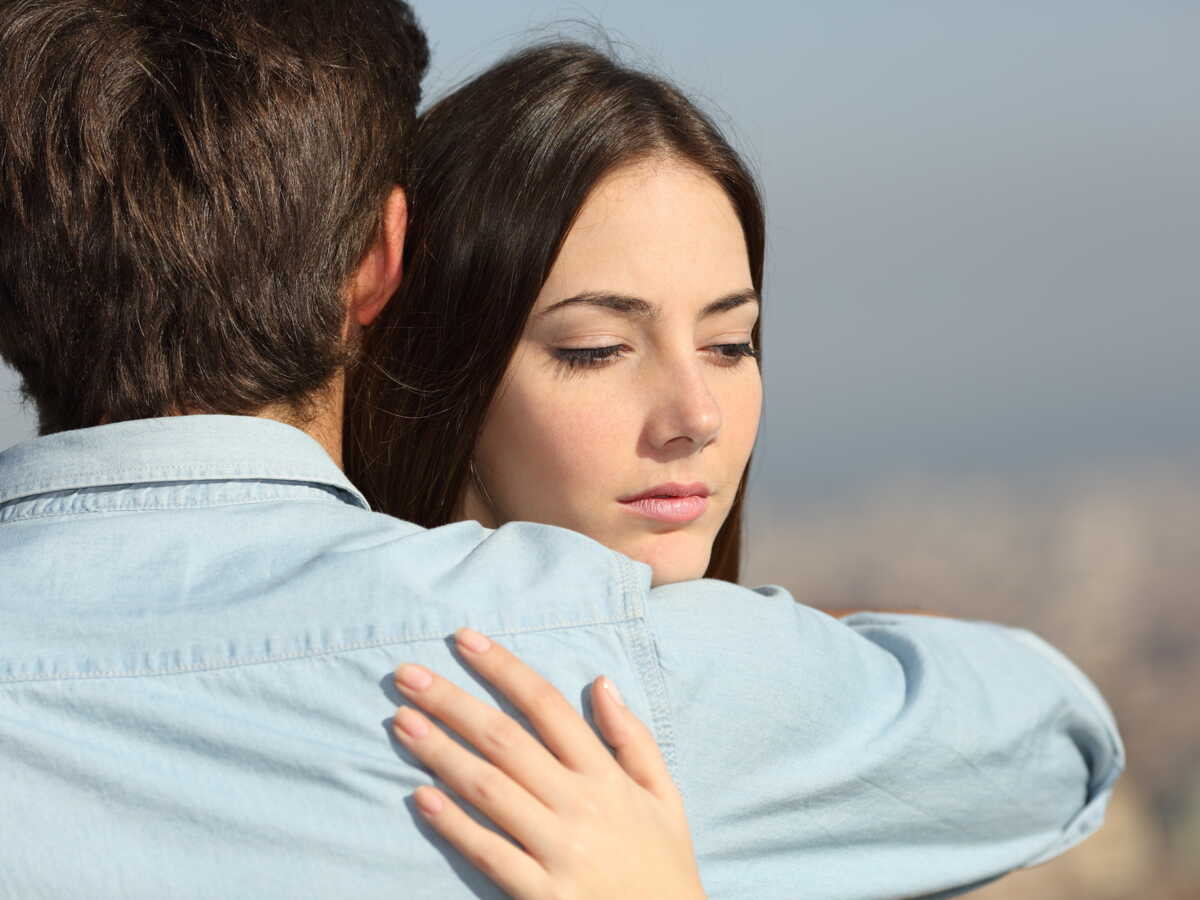 Une femme sentant un vêtement avec une expression pensive.