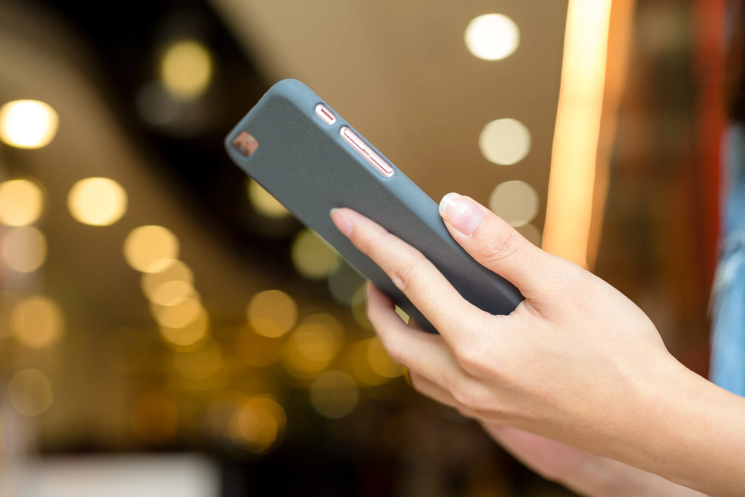 Main tenant un smartphone et utilisant les boutons latéraux