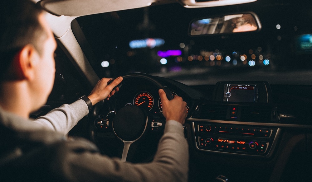Jeune conductrice regardant la route de nuit avec attention