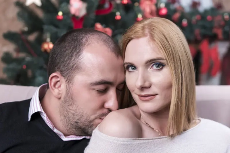 Un homme réconforte une femme par un baiser sur l'épaule, geste de soutien.