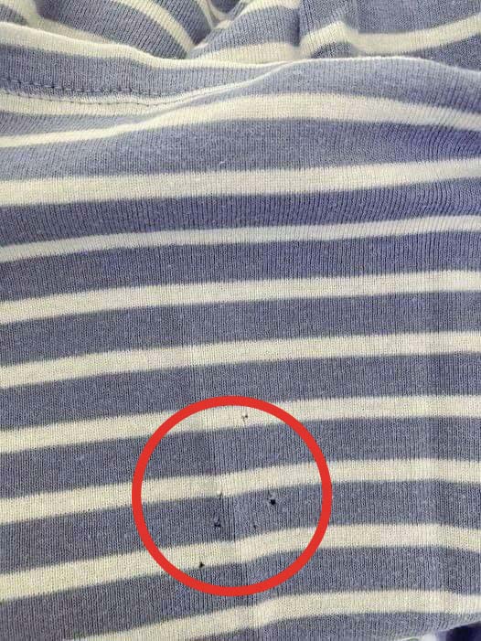 Détail d'un petit trou dans un t-shirt près de la taille