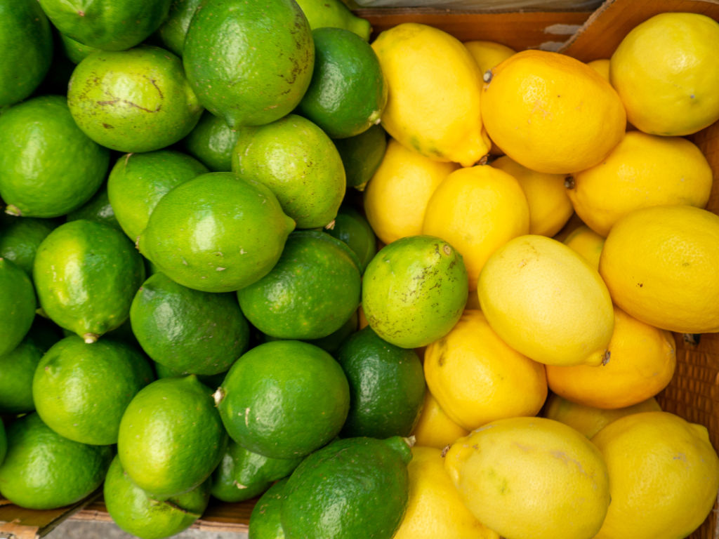 Citrons et limes dans une cagette formant un fond avec différents agrumes