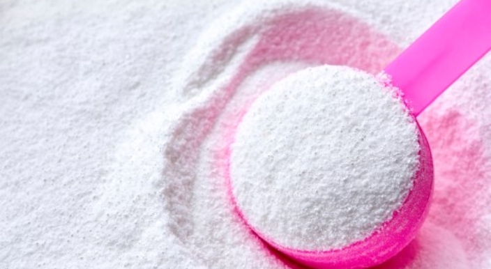 Cuillère doseuse remplie de lessive en poudre