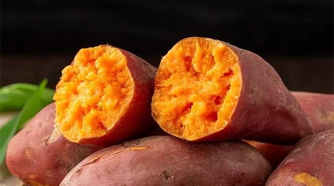 Patate douce coupée en deux sur une planche en bois, prête à être cuisinée pour le petit-déjeuner