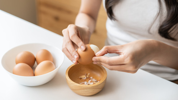 Personne épluchant un œuf dur avec facilité, coquille qui se détache bien